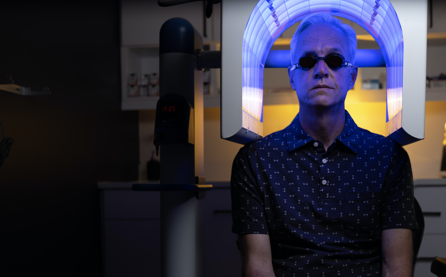 Man sitting under blue light wearing goggles